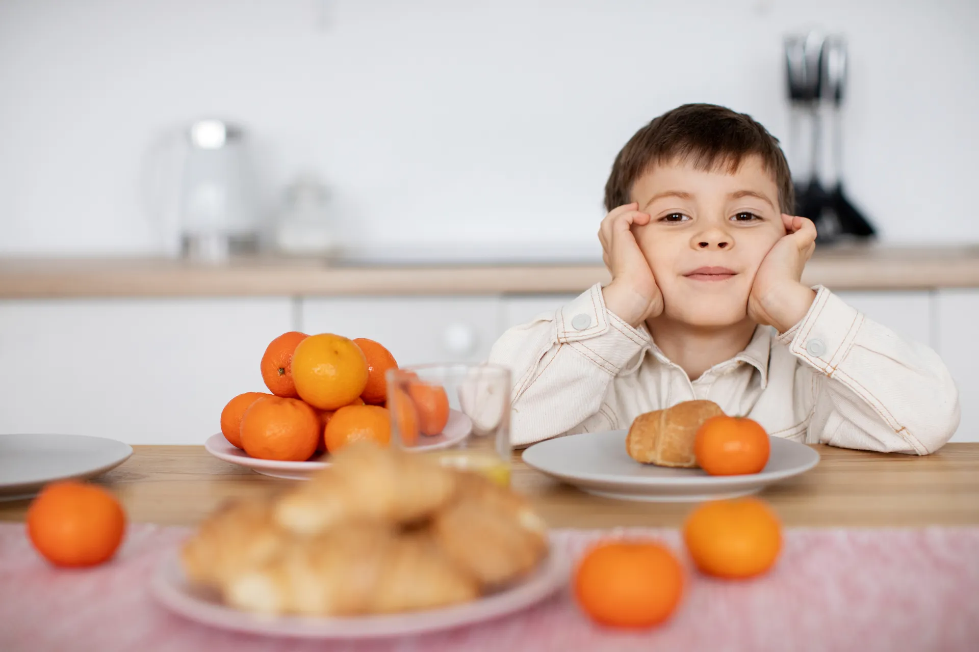 Criança sorrindo à mesa com frutas