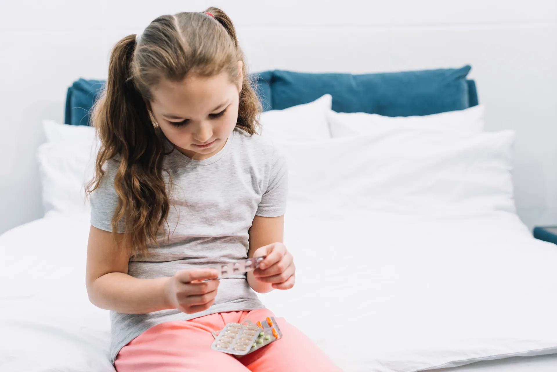 Menina segurando cartela de medicamentos